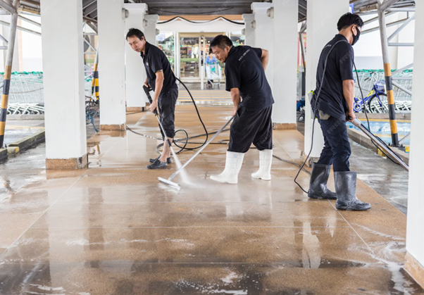 Three men pressure washing an outdoor tiled floor.